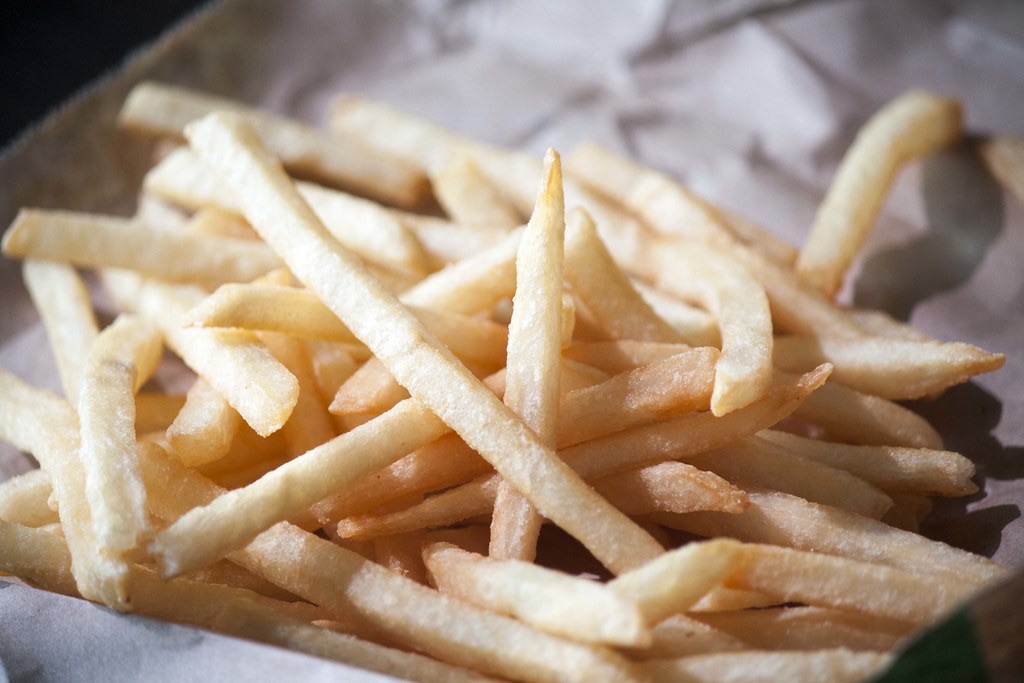 Gebakken friet op vetvrij papier, van dichtbij.